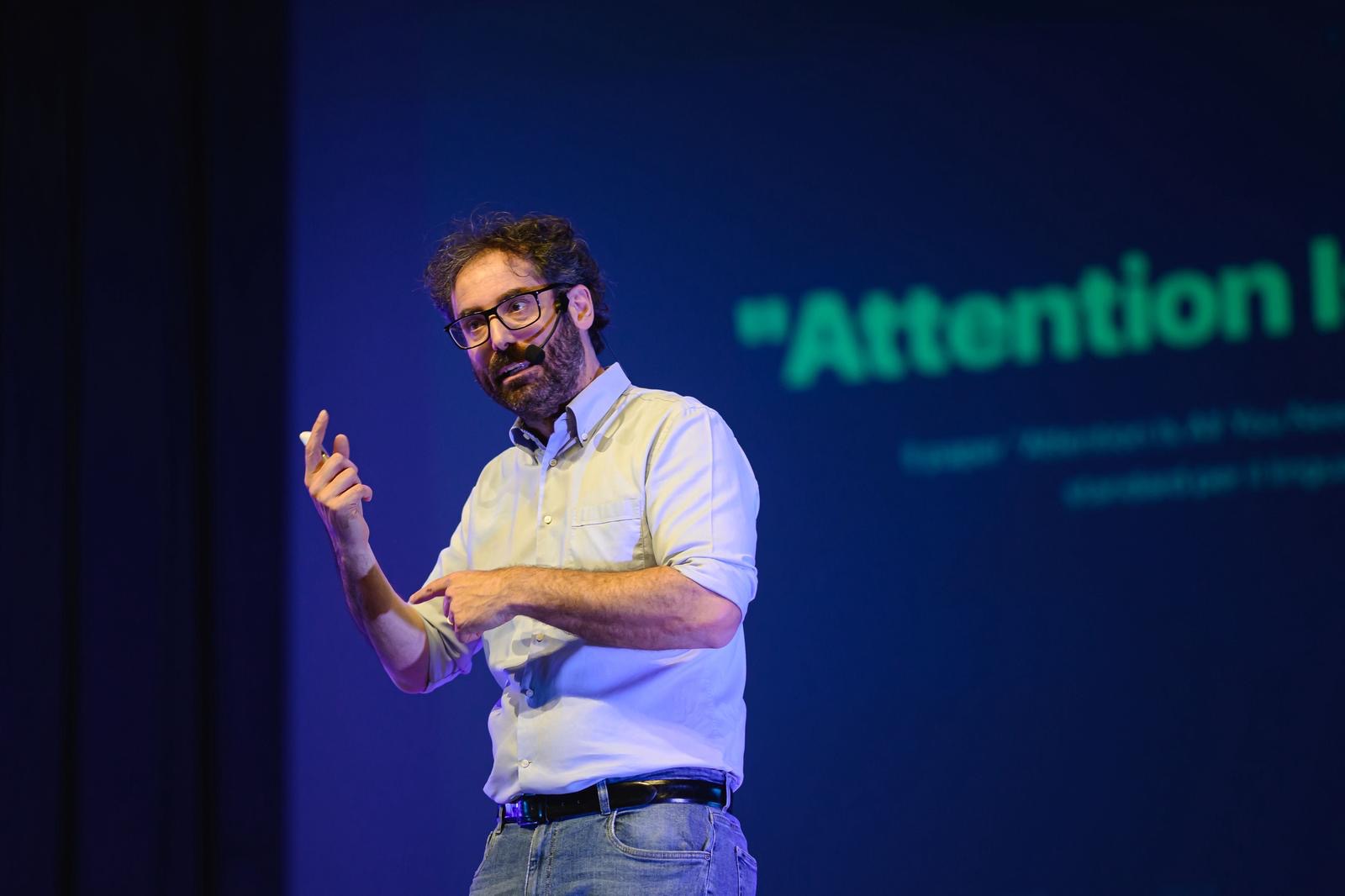 Mattia Crivellini spiega il meccanismo di attenzione dei Transformer, con la scritta «Attention Is All You Need» sullo schermo
