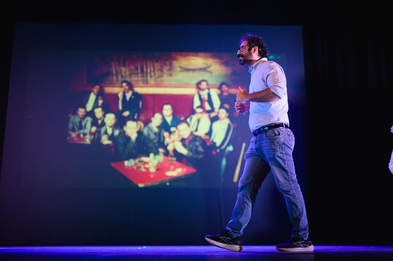 Mattia Crivellini attraversa il palco durante lo spettacolo, con un'immagine proiettata sullo schermo